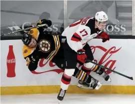  ?? NAncy LAnE / hErALd sTAFF ?? COMPETE LEVEL IN SHAMBLES: Bruins winger Karson Kuhlman is checked into the boards by Devils center Yegor Sharangovi­ch at the Garden on Sunday.