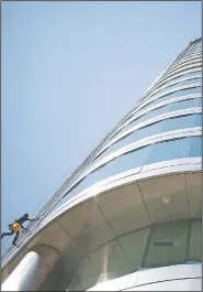  ??  ?? Murrin hangs from the side of the building while wiping a window. He said he uses Dawn dish soap for cleaning.