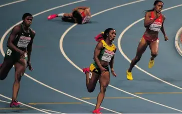  ?? ANTONIN THUILLIER/AFP/GETTY IMAGES ?? Olympic champ Allyson Felix falls as Jamaica’s Shelly-Ann Fraser-Pryce, centre, heads for the gold in the 200-metre final at the world championsh­ips in Moscow Friday.