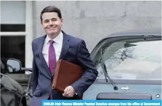  ??  ?? DUBLIN: Irish Finance Minister Paschal Donohoe emerges from his office at Government Buildings for a photocall with the 2018 budget in Dublin yesterday.—AFP