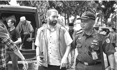  ??  ?? Dorfin is escorted during his arrival at a court in Mataram, West Nusa Tenggara. — AFP photo