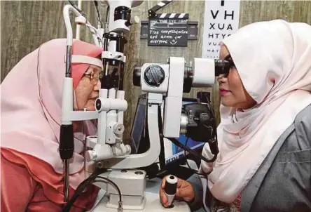  ??  ?? Siti Fairuz (kanan), memeriksa mata pelanggann­ya.