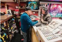  ?? ?? Jairo Cardenas, left, owner the Alpha Shoe Repair Corp., shows the repair made on a customer’s shoes on Feb. 3 in New York. Business at the shop, which Cardenas has run for 33 years, is down 75% compared with prior to the pandemic. Shoe repairs typically bring in more money than shines.