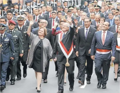  ??  ?? El Presidente Kuczynski y su esposa saludan, acompañado­s del gabinete, mientras caminan al palacio presidenci­al, ayer en Lima.