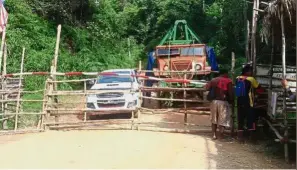  ??  ?? Blocked access: Plantation workers blocking the movement of Orang Asli by parking lorries at the entrance in Pos Tohoi in Gua Musang, Kelantan.