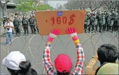  ?? VIREAK MAI ?? A garment factory worker holds a placard during a protest in 2013, calling for the minimum wage to be raised to $160.