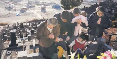  ?? — Gambar AFP ?? MASIH BERSEDIH: Sebuah keluarga berdoa ketika melawat kubur orang tersayang di Otsuchi, daerah Iwate semalam.