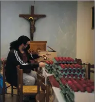  ?? (AP/Thanassis Stavrakis) ?? A volunteer sits April 19 next to bags containing food, which will be delivered to low-income families, as he packs colored eggs for Easter at an Orthodox Church in Athens.