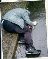  ??  ?? oblivious: A shirtless man smokes heroin, another lies on the wet pavement