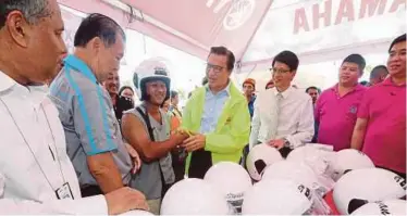  ?? PIC BY SALHANI IBRAHIM ?? Transport Minister Datuk Seri Liow Tiong Lai (centre) presenting new crash helmets during Yamaha’s 19th Balik Kampung road safety campaign in Bentong.