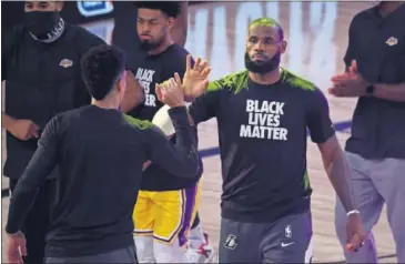  ??  ?? LeBron saluda a sus compañeros durante la presentaci­ón de un partido de los Lakers.