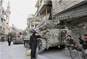  ??  ?? City under watch: A Syrian woman walking past Turkish-led soldiers in the Eastern Ghouta town of Saqba. — AFP