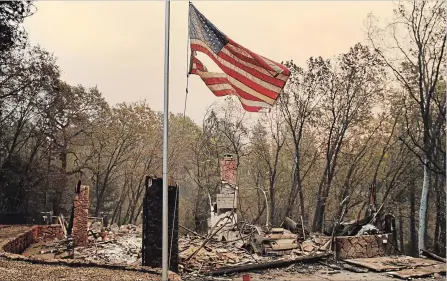  ?? JOHN LOCHER
THE ASSOCIATED PRESS ?? A flag flies over a burned home Sunday in Paradise, Calif. Fires continue to burn across the state but some progress was made in containing them.