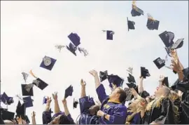  ?? Matt Rourke Associated Press ?? AMID A TIGHT labor market, some employers hope to entice new hires with student loan payments. Above, graduates toss their caps in Philadelph­ia in 2015.