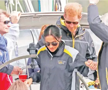  ?? — Reuters photo ?? Prince Harry and Meghan disembark a friend’s boat after watching the sailing event of the Invictus Games at Farm Cove in Sydney, Australia, yesterday.