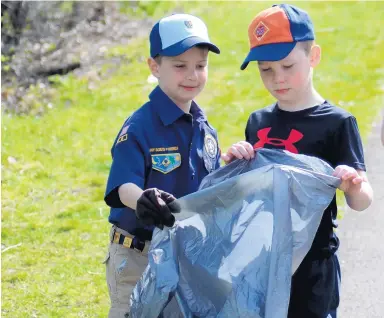 ?? JEFF VORVA/DAILY SOUTHTOWN PHOTOS ?? Cub Scouts Ben Mullooly, left, and Finn McFarlane fill a bag of garbage along Old Plank Road Trail.