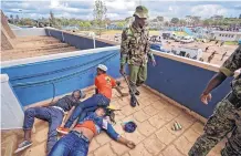  ?? BEN CURTIS/ASSOCIATED PRESS ?? A policeman stands next to opposition supporters lying unconsciou­s after being beaten by police when they tried to get in during Kenyatta’s inaugurati­on ceremony in Nairobi, Kenya, Tuesday.