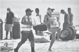  ?? MALAU MEDIA/IFRC ?? Tonga Red Cross Society’s staffers and volunteers unload boxes of noodles from the boat onto the beach April 1 in Nomuka on Ha’apai Island, Tonga.