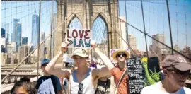  ?? THE ASSOCIATED PRESS ?? Activists carry signs across the Brooklyn Bridge during a rally to protest the Trump administra­tion’s immigratio­n policies Saturday in New York.