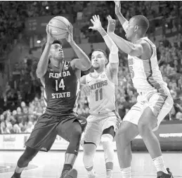  ?? RON IRBY/ASSOCIATED PRESS ?? Florida State guard Terance Mann (14) drives against Florida guard Chris Chiozza (11) and forward Keith Stone (25) during the first half on Monday night in Gainesvill­e.