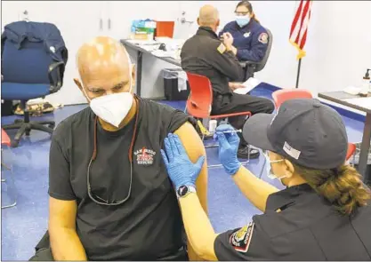  ?? EDUARDO CONTRERAS U-T ?? Engineer Jennifer Wolf (right) gives the Pfizer COVID-19 vaccine to Kelly Zombr, deputy fire chief, at the San Diego Fire-Rescue Department’s training facility on Thursday. More than 300 were set to receive doses. See story, A6.