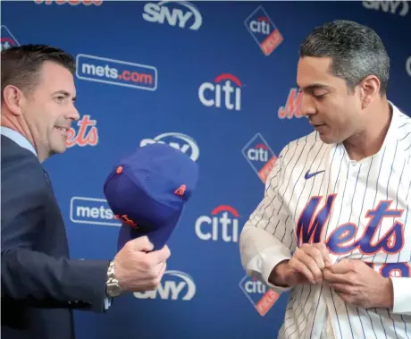  ??  ?? Luis Rojas, se coloca la chaqueta, mientras el gerente general Brodie Van Wagenen le pasa la gorra del club.