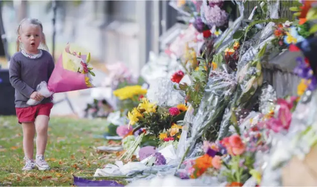  ?? Associated Press ?? A girl carries flowers to a memorial wall following the mosque shootings in Christchur­ch, recently.