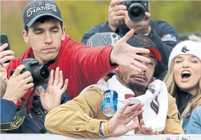  ?? ELISE AMENDOLA THE ASSOCIATED PRESS ?? A Red Sox staff member, left, tries to protect right fielder Mookie Betts from a beer can during Wednesday’s World Series parade.