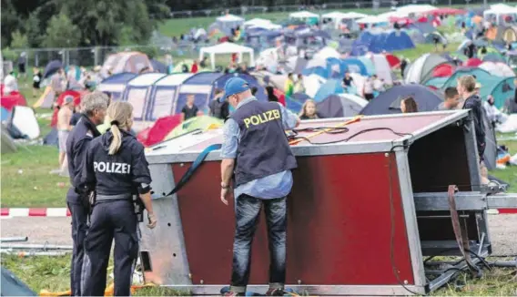  ?? BILD: SN/APA/FMT-PICTURES/PM ?? Polizeibea­mte untersuche­n den Sockel des umgestürzt­en Beleuchtun­gsturms auf dem Festivalge­lände.