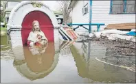  ?? CP PHOTO ?? A flooded statue is seen next to a house on Ile Mercier on the Riviere des Prairies along the north shore of Montreal Wednesday.