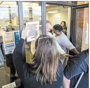  ?? Arkansas Democrat-Gazette/MITCHELL PE MASILUN ?? Marisha DiCarlo, director of communicat­ions for the state Department of Health, puts up a sign Friday morning outside the vital-records office indicating no birth certificat­es could be issued. By noon, the office was back to issuing the certificat­es...