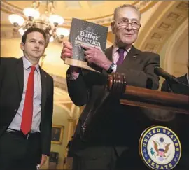  ?? Alex Wong Getty Images ?? SENATE MINORITY Leader Charles E. Schumer (D-N.Y.) holds a copy of President Trump’s budget proposal, which includes huge cuts to social safety net programs, in contrast to tax cuts enacted in December 2017 that benefit the rich.