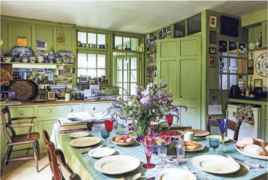  ??  ?? ABOVE The kitchen table, also Rory’s desk, is laid for lunch with turned wooden plates made by Judith Verity. Woodwork and panelling are painted a soft green, subtly stippled by craftsman- painter Mike Reynolds. The 18th- century Chinese export...