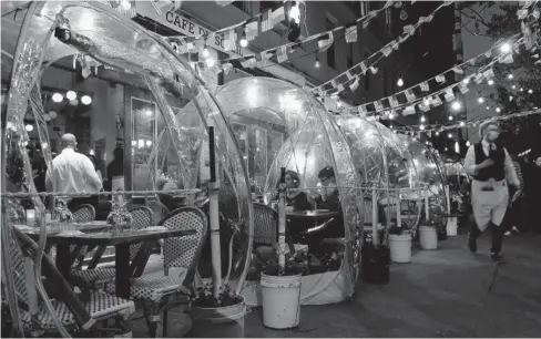  ?? FOTO: AFP ?? > La gente cena en carpas de plástico para el distanciam­iento social en un restaurant­e en Manhattan, en Nueva York.