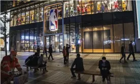  ?? Photograph: Kevin Frayer/Getty Images ?? People walk by and sit outside the NBA flagship retail store in Beijing last year.