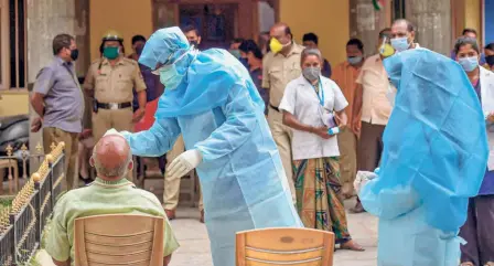  ??  ?? COLLECTING samples for swab test of primary contacts of a policeman who tested positive at the Kalasipaly­a police station in Bengaluru, on June 16. (Facing page) Migrants from Uttar Pradesh at Palace Grounds in Bengaluru ready to depart on June 16.