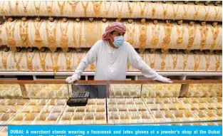  ?? — AFP ?? DUBAI: A merchant stands wearing a facemask and latex gloves at a jeweler's shop at the Dubai Gold Souq on May 12, 2020.