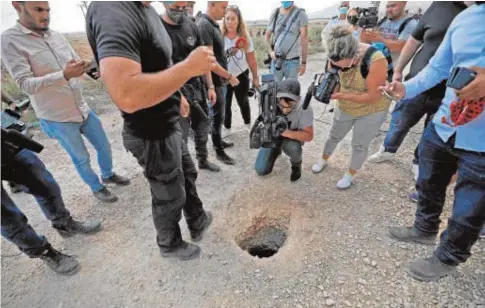  ?? // AFP ?? La Policía y varios periodista­s observan el agujero por el que se fugaron los palestinos