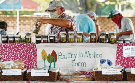  ?? Adam Robison / Associated Press ?? Kevin Guyer stocks canned pickles and other items at his booth inside the Oxford, Miss., Farmer’s Market.