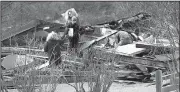  ?? AP/The Republican/DAVID MOLNAR ?? People go through the flattened remains of a barn at J&amp;J Maggs Antiques in Conway, Mass., on Sunday, the day after a storm blew through the town. The storm heavily damaged several buildings, tearing off roofs and knocking down walls.