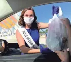  ?? ABBY NG/MILWAUKEE JOURNAL SENTINEL ?? Julia Nunes, 73rd Alice in Dairyland, in matching sash and mask, delivers pork sandwiches and burgers at the Pork Schoppe Tent.