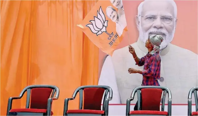  ?? Agence France-presse ?? A worker fixes a BJP flag on a hoarding of Narendra Modi in Raipur on Monday.