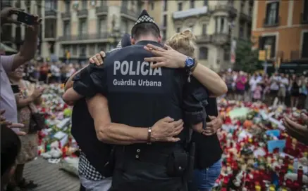  ?? SANTI PALACIOS, THE ASSOCIATED PRESS ?? A police officer hugs a family that he helped during the terrorist attack, at a memorial on Las Ramblas, Barcelona, Spain, on Monday.
