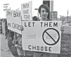  ?? LEONARD HAYHURST/TRIBUNE ?? Christophe­r Brown, with three children in Coshocton City Schools, stands in front of the main entrance Monday morning with a sign protesting a mask requiremen­t voted on by the board of education on Thursday.