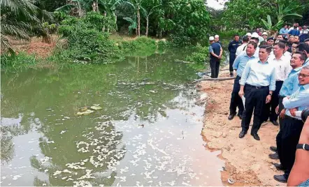  ??  ?? First-hand look: Azmin (front row, third from right) checking out the contaminat­ed Sg Buah after workers blocked it from flowing into Sg Semenyih.