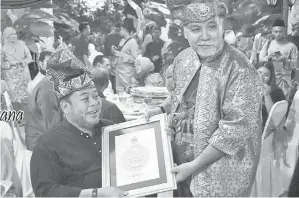  ??  ?? ILYAS (kanan) menyampaik­an sijil penghargaa­n kepada Awang.
