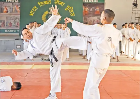  ?? ?? Indo-Tibetan Border Police train recruits in 15 martial arts, above. Officers from India and China engage in a hands-on battle in the border dispute, below