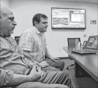  ?? MIKE PARKER / CEDAR PARK-LEANDER STATESMAN ?? City traffic signal coordinato­r Ali Mozdbar (left) and city director of utilities Eric Rauschuber look at a traffic signal synchroniz­ation program at the public works department. The city hired Mozdbar to improve mobility on city streets.