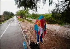  ?? Fernando Llano / Associated Press ?? A Venezuelan migrant stands covered in a wrap while texting, on the banks of the Rio Grande in Matamoros, Mexico on Saturday.