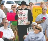  ?? THE ASSOCIATED PRESS ?? Walden Paige, of Marshallto­wn, Iowa, center, watches during a rally to protest the Trump administra­tion's immigratio­n policies Saturday outside the Marshall County Courthouse in Marshallto­wn, Iowa.